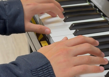 niño aprendiendo canciones fáciles al piano con partitura